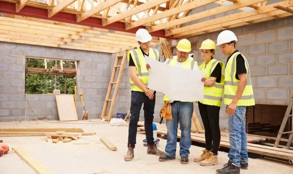 Grupo de trabajadores de construcción revisando planos y asegurando el cumplimiento de estándares de calidad y seguridad en la obra.