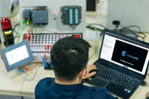 Ingeniero trabajando en laptop con programación en PLC para integrar variadores, sensores y sistemas industriales escalables.