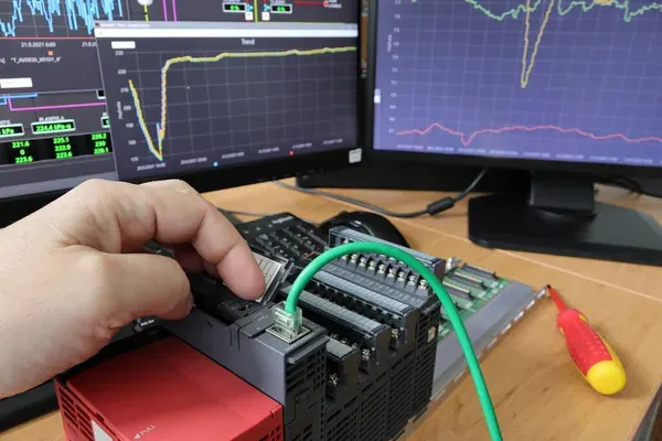 Primer plano de una mano reiniciando un PLC